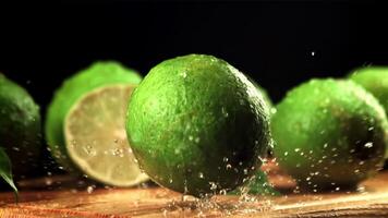 Lime falls on a cutting board with splashes of water. On a black background.Filmed is slow motion 1000 fps. High quality FullHD footage video