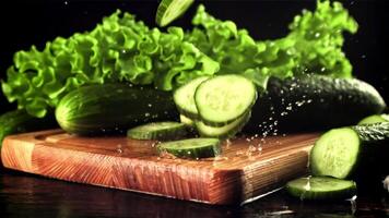 Pieces of cucumber fall on a cutting board with splashes of water. On a black background. Filmed is slow motion 1000 fps. High quality FullHD footage video