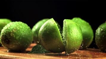 das Limette Stürze auf das Schneiden Tafel und spaltet sich in Hälften. auf ein schwarz Hintergrund.gefilmt ist schleppend Bewegung 1000 fps. video