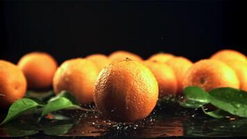 un jugoso Mandarina caídas en el mesa con salpicaduras de agua. en un negro fondo.filmado es lento movimiento 1000 marcos por segundo. video