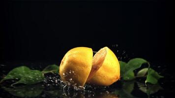 The lemon falls on the table and splits into two halves. On a black background. Filmed is slow motion 1000 fps. video