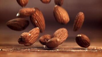 Almendras, un natural ingrediente, son cascada sobre un de madera mesa. esta de cerca, macro fotografía vitrinas el nueces en su caparazón, retratar un todavía vida de natural comidas video