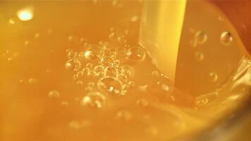 A stream of orange juice pours into a glass with air bubbles. Macro background.Filmed is slow motion 1000 fps. High quality FullHD footage video