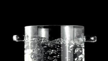 en pott av flytande är kokande på en svart bakgrund, skapande en vätska rörelse. de transparent drinkware speglar de ljus tycka om en rektangel av glas under bil- belysning video