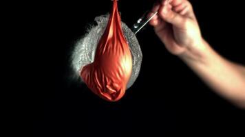 A dynamic showcases colorful closeup shots of a person inflating a red balloon, splashing water, and holding a red object in a water splash on a black background video