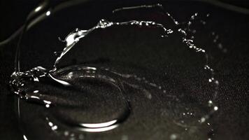 macro la photographie capturé une fermer de une Collier brillant avec humidité sur une noir surface. le éclat la photographie Souligné le gouttelettes à créer une étourdissant image dans le obscurité video