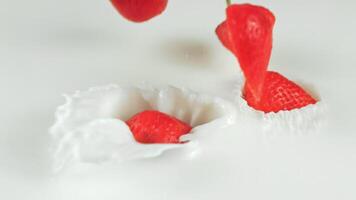 fascinante lento movimiento de fresas y golosinas suavemente que cae dentro cremoso leche, creando maravilloso remolinos y salpicaduras ideal para comida y bebida anuncios o cautivador social medios de comunicación contenido video