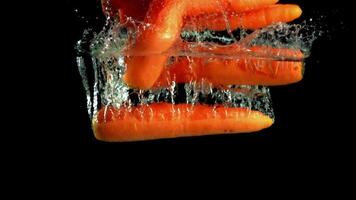 Super slow motion ripe carrots with spray falls into the water. Filmed on a high-speed camera at 1000 fps. High quality FullHD footage video