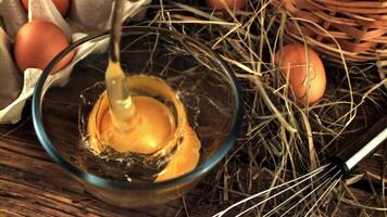 Super slow motion raw egg falls into a transparent bowl on the table. On a wooden background. Filmed on a high-speed camera at 1000 fps. video