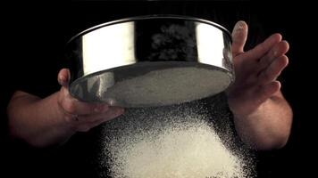 Super slow motion of the man's hand sift the flour through a baking sieve. Filmed on a high-speed camera at 1000 fps.On a black background. High quality FullHD footage video