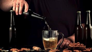 Super schleppend Bewegung Hand Mann gießt Bier in ein Glas von das Flasche. auf ein schwarz Hintergrund. gefilmt auf ein schnelle Geschwindigkeit Kamera beim 1000 fps. video