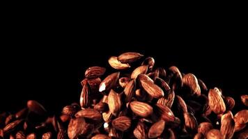 Mesmerizing macro photography capturing a pile of almonds falling dramatically on a dark background, creating a visually stunning image video