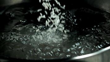 Rice is being added to a pot of boiling liquid, resembling a dark event in monochrome photography video