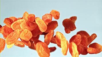 A heap of dried apricots, a natural ingredient, sits on a vibrant blue background resembling the sky. This fruit is commonly used in cuisine and dishes, adding a sweet touch to meals video