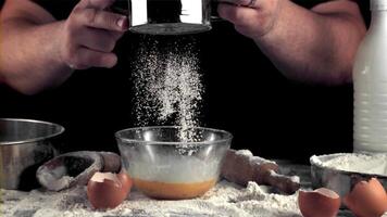 Super slow motion men's hands sprinkle flour in a bowl for baking. On a black background. Filmed on a high-speed camera at 1000 fps. video