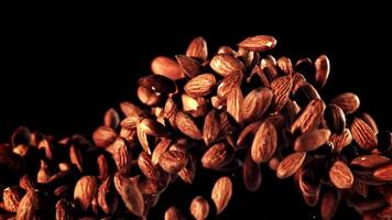 An entertainment event showcasing a pile of almonds on a black background, captured in a still life photography with a touch of darkness and wood accents. A perfect blend of food and art video