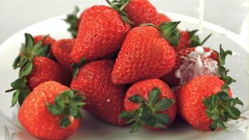 Super slow motion on fresh strawberries in a plate pours milk. On a white background. Filmed on a high-speed camera at 1000 fps video