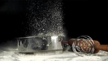 súper lento movimiento tamiz caídas en el mesa con harina y batidor. en un negro fondo.filmado en un alta velocidad cámara a 1000 fps. video