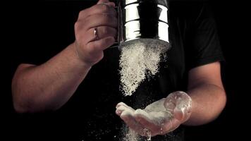 Super slow motion men's hands sift the flour to make cookies. On a black background. Filmed on a high-speed camera at 1000 fps.High quality FullHD footage video