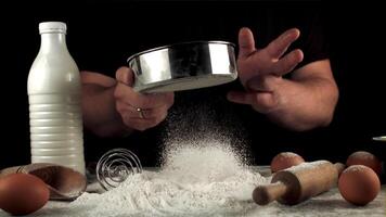 Super slow motion of the man's hand sift the flour through a baking sieve. Filmed on a high-speed camera at 1000 fps.On a black background. video