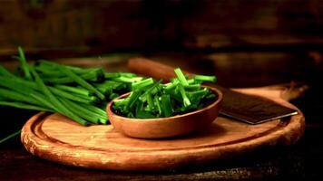 Super slow motion plate with chopped green onion falls on the table. Filmed at 1000 fps.On a wooden background. video