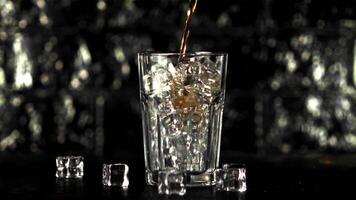 Super slow motion in a glass with ice cubes pours cola. Filmed at 1000 fps.On a black background. video