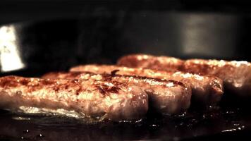 Super slow-moving sausages are fried with bubbles of oil and hot steam. On a black background.Filmed on a high-speed camera at 1000 fps. video