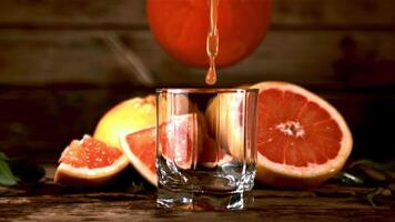 Super schleppend Bewegung Grapefruit Saft gegossen in ein Glas von Krug. auf ein hölzern Hintergrund.gefilmt auf ein schnelle Geschwindigkeit Kamera beim 1000 fps. video