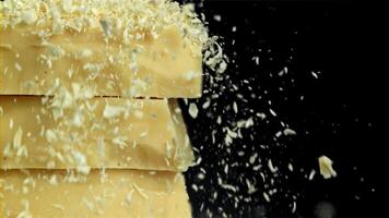 Shredded white chocolate falls on a tower of chocolate pieces. Filmed on a high-speed camera at 1000 fps. High quality FullHD footage video