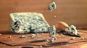 super langzaam beweging blauw kaas valt Aan een houten tafel. gefilmd Aan een hoge snelheid camera Bij 1000 fps. hoog kwaliteit full HD beeldmateriaal video