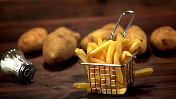 súper lento movimiento cesta con francés papas fritas caídas en el mesa. filmado en un alta velocidad cámara a 1000 fps.on un de madera antecedentes. video