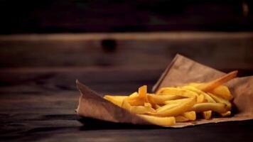 Super slow motion French fries on paper falls on the table and scatters. Filmed at 1000 fps.On a wooden background. video