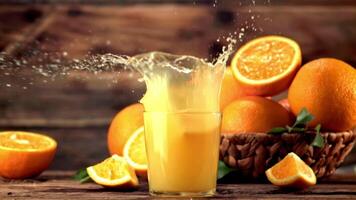 Super slow motion in a glass with orange juice drops a piece of orange with splashes.Filmed at 1000 fps. On a wooden background. video