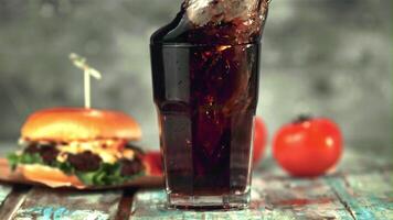 Super slow motion in a full glass with cola falls ice cubes. On a gray background. Filmed on a high-speed camera at 1000 fps. video