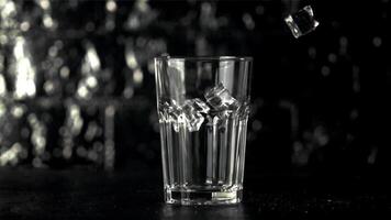 Super schleppend Bewegung Eis Würfel fallen in ein Glas auf das Tisch. auf ein schwarz Hintergrund.gefilmt auf ein schnelle Geschwindigkeit Kamera beim 1000 fps. video