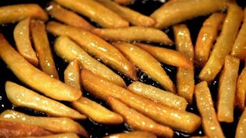 súper lento movimiento de papas fritas es frito en un fritura pan con burbujas de aceite. filmado en un alta velocidad cámara a 1000 fps.on un negro antecedentes. video