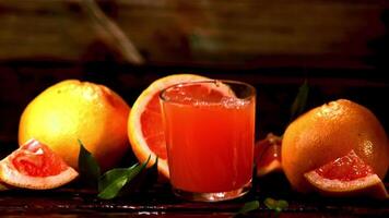 Super slow motion glass with grapefruit juice falls on the table. Filmed at 1000 fps.On a wooden background. video