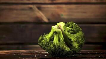 super langzaam beweging stukken van broccoli vallen Aan de tafel met spatten van water. gefilmd Bij 1000 fps.aan een houten achtergrond. video