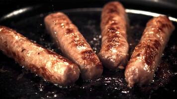 Super slow motion sausages are fried in a frying pan with splashes of oil. Filmed on a high-speed camera at 1000 fps.On a black background. video