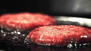 super lento comovente cru hamburguer é frito com óleo salpicos e quente vapor. filmado em uma alta velocidade Câmera às 1000 fps.ligado uma Preto fundo. video