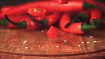 Super slow motion pieces of chilli pepper fall on the cutting board. On a wooden background. Filmed on a high-speed camera at 1000 fps. High quality FullHD footage video