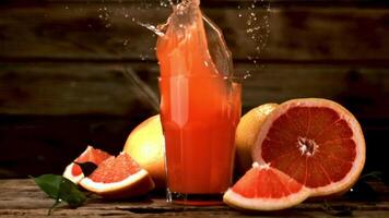 super lento movimento dentro uma vidro com Toranja suco cai uma peça do Toranja com spray. filmado em uma alta velocidade Câmera às 1000 fps.ligado uma de madeira fundo. video