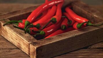 super langzaam beweging dienblad met chili peper valt Aan de tafel. Aan een houten achtergrond. gefilmd Aan een hoge snelheid camera Bij 1000 fps. hoog kwaliteit full HD beeldmateriaal video