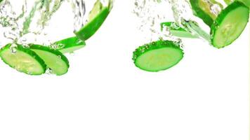 Super slow motion chopped cucumbers fall under the water with air bubbles. On a white background. Filmed on a high-speed camera at 1000 fps. High quality FullHD footage video