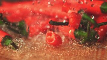 Super slow motion on pieces of red chilli pepper drops water. On a wooden background. Filmed on a high-speed camera at 1000 fps. High quality FullHD footage video