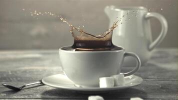 A super slow motion piece of sugar falls into the coffee with splashes. On a gray background. Filmed on a high-speed camera at 1000 fps. video