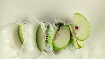 Super slow motion apple pieces fall into the milk with splashes. On a white background. Filmed on a high-speed camera at 1000 fps. Top view video