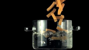 super lento movimento nel un' padella con bollente acqua caduta pasta. su un' nero sfondo.filmato su un' alta velocità telecamera a 1000 fps. video