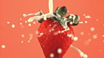 Super slow motion on the rotating strawberries pours milk. On a pink background. Filmed on a high-speed camera at 1000 fps video