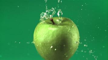 Super slow motion water droplets fall on a rotating fresh apple. On a green screen.Filmed on a high-speed camera at 1000 fps video